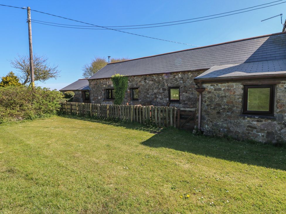 An outdoor view of a property with a stone wall and grassy area at Butterslade in Port Eynon