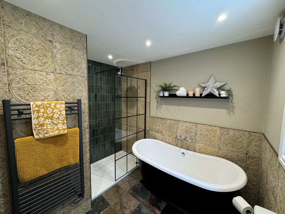 A bathroom with a bathtub and shower at The Stables in Prestatyn