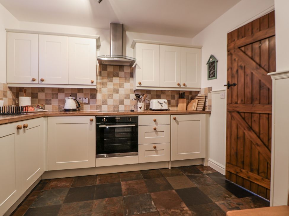 A kitchen with cabinets and an oven at The Stables in Prestatyn
