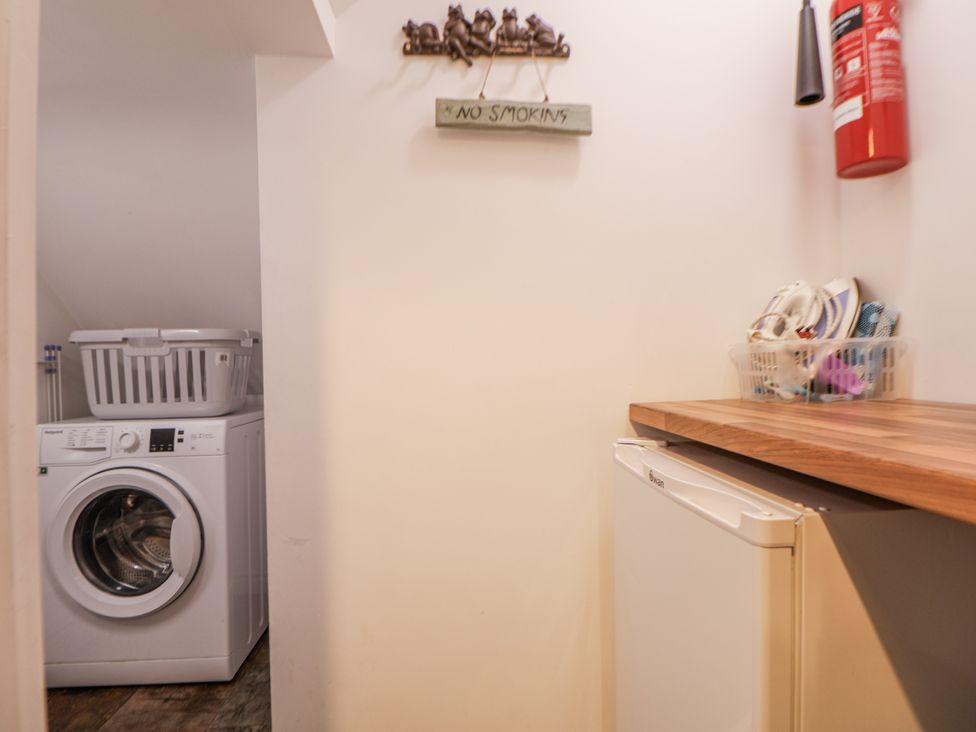 A laundry room with a washing machine and fridge at The Stables in Prestatyn