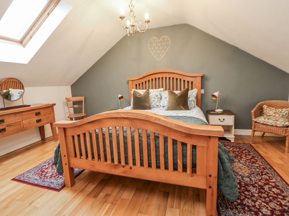 A bedroom with a wooden bed and bedside table at The Stables in Prestatyn