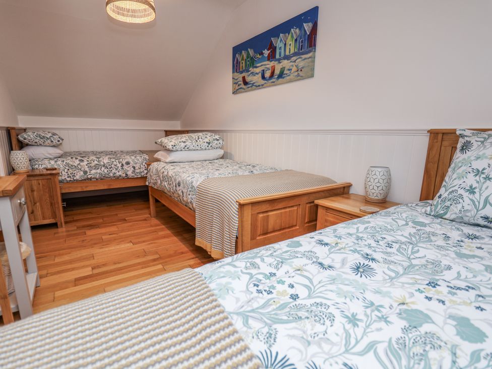 A bedroom with two beds and a painting on the wall at The Stables in Prestatyn
