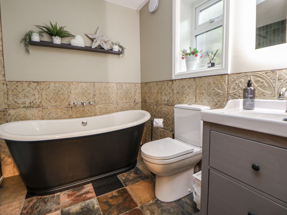 A bathroom with a bathtub, toilet and sink at The Stables in Prestatyn
