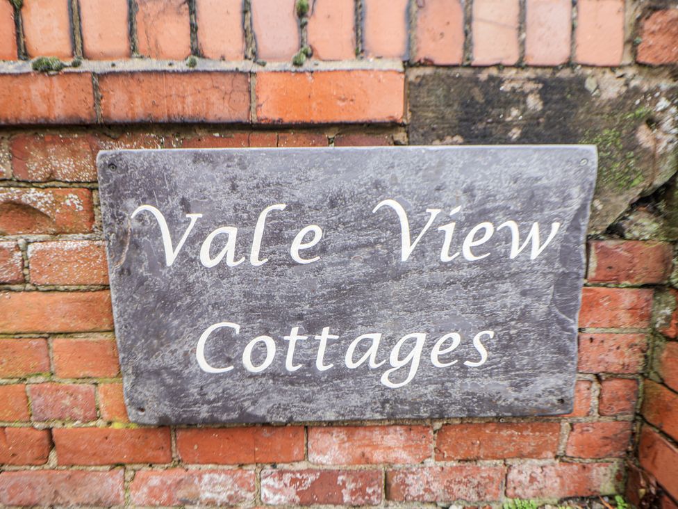 A sign reading Vale View Cottages on a brick wall