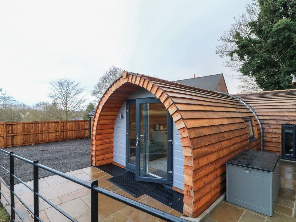 A wooden cabin with a curved roof and door at Park View Lodge