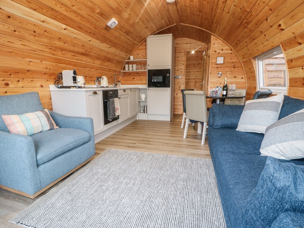 A living room with a sofa and kitchen area at Park View Lodge