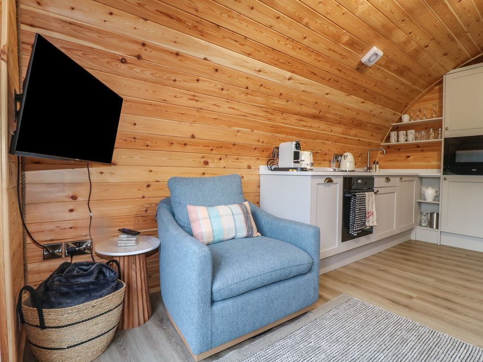 A living room with an armchair and kitchen units at Park View Lodge in 