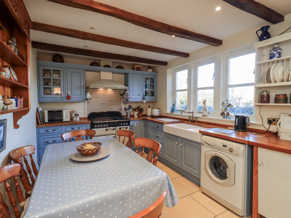 A kitchen with cabinets, dining table and washing machine at Orchard House Leyburn