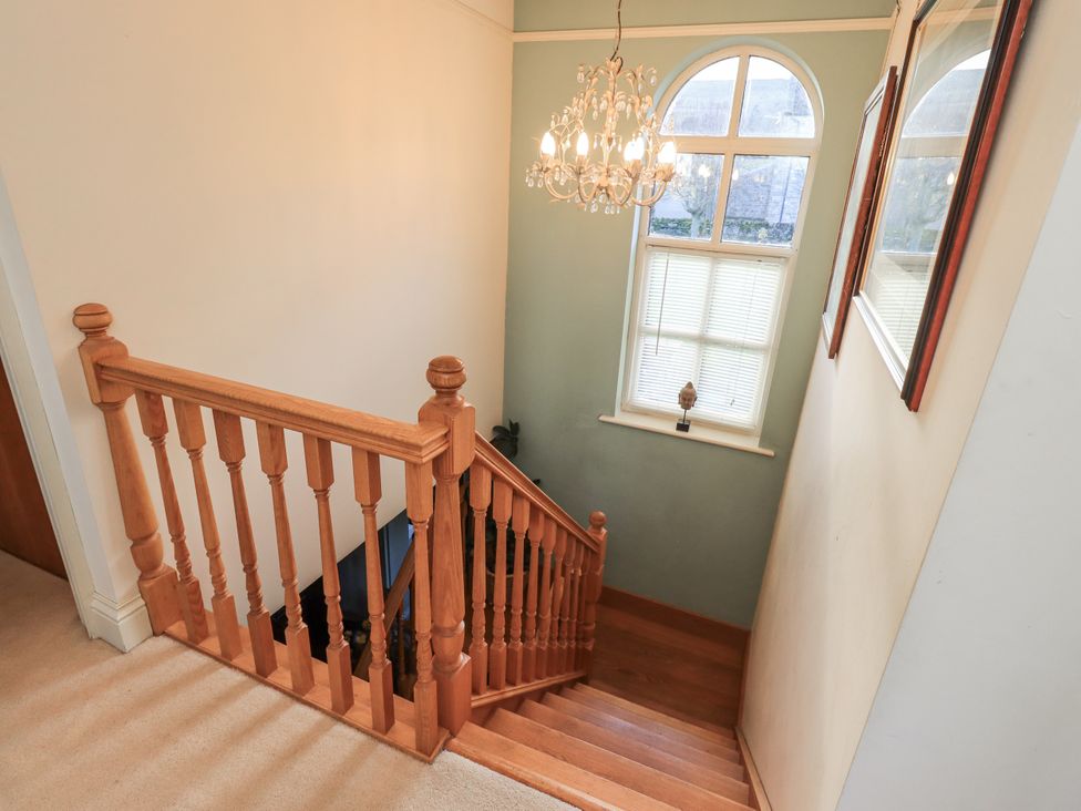 A staircase with chandelier and window in the hallway at Orchard House Leyburn