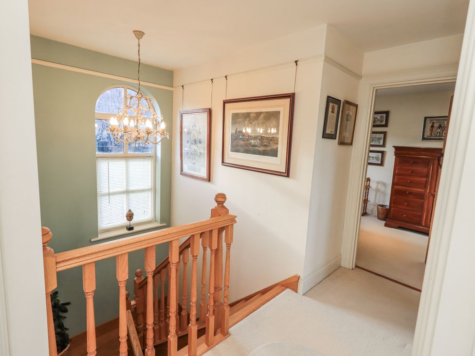A hallway with a chandelier and staircase at Orchard House in Leyburn