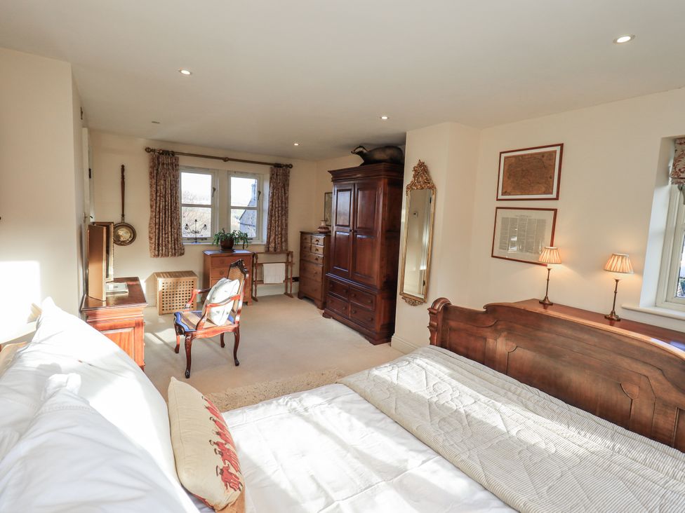 A bedroom with a bed, wardrobe, chair and desk at Orchard House in Leyburn