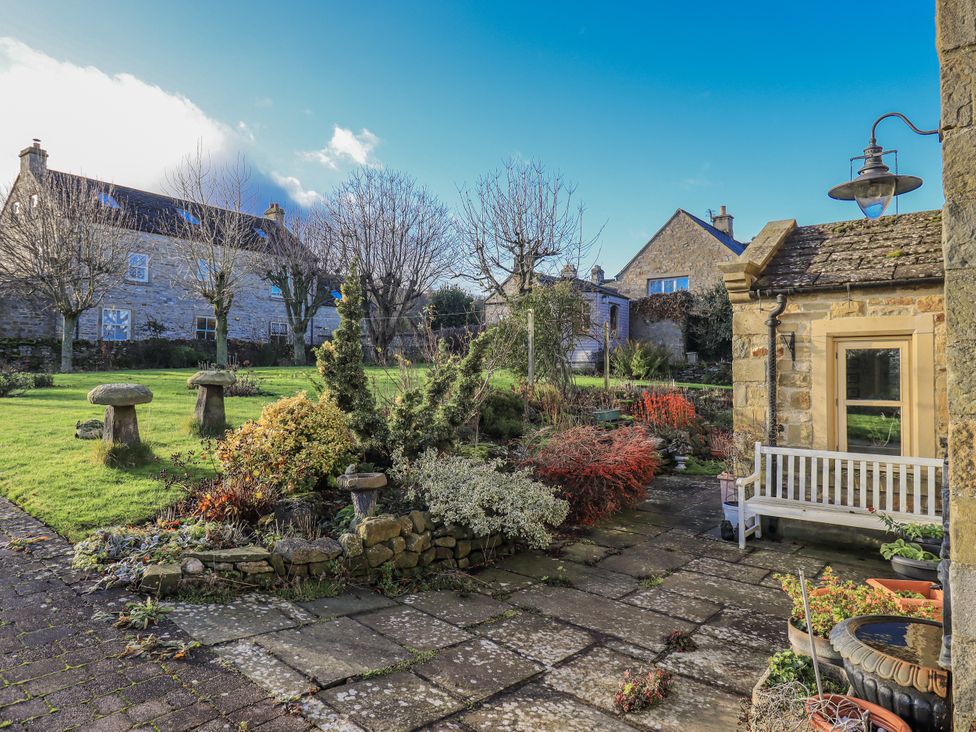 A garden with flower beds and stone pathway at Orchard House Leyburn