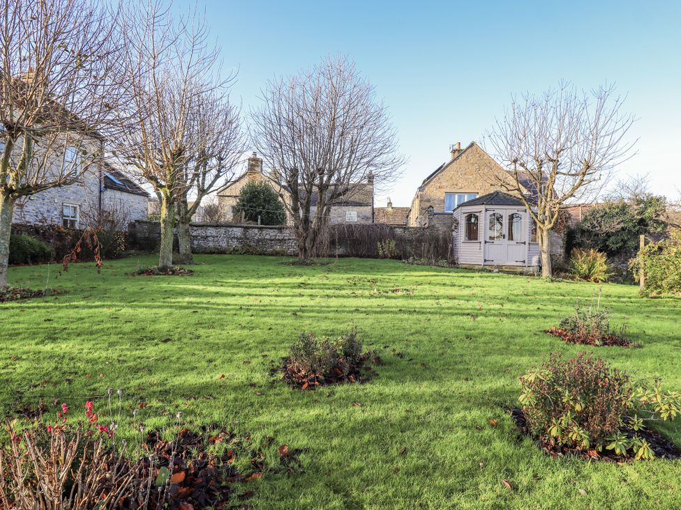 A garden with grass and trees at Orchard House Leyburn
