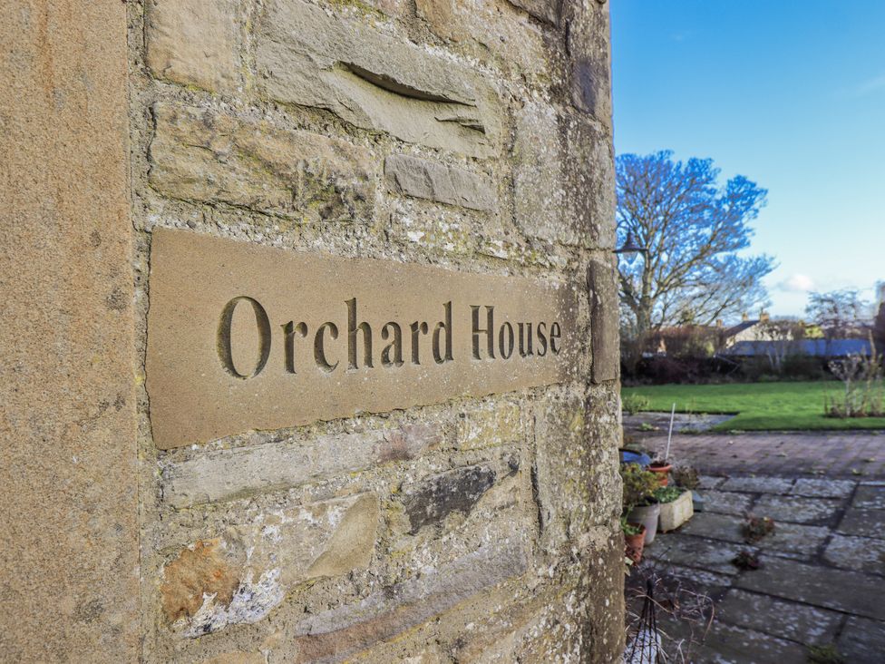 A stone wall with a sign at Orchard House Leyburn