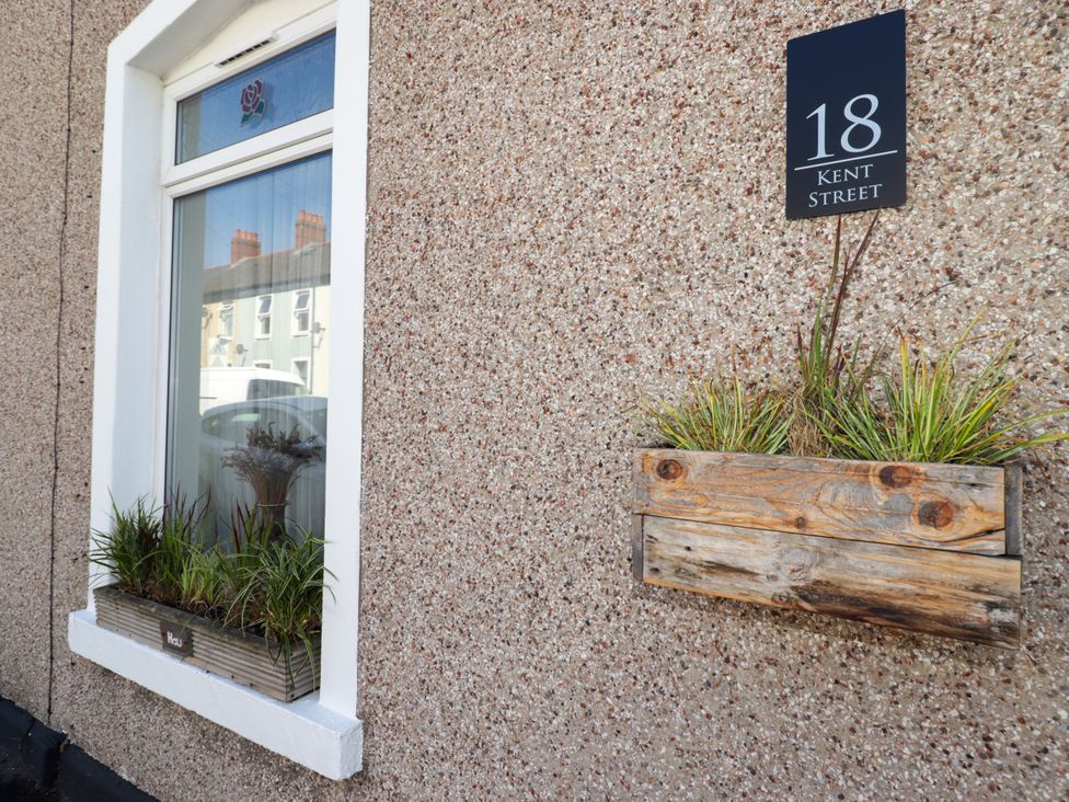 A window with plants and an address sign at 18 Kent Street in Cardiff