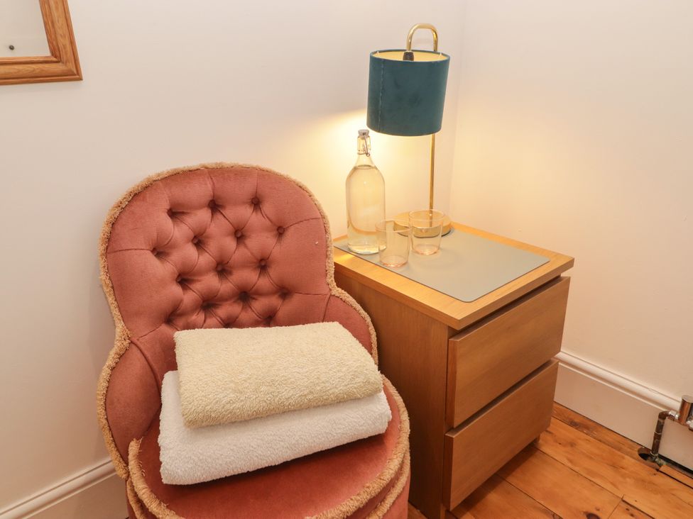 A snug with an armchair, lamp, side table, and glassware at 18 Kent Street in Cardiff