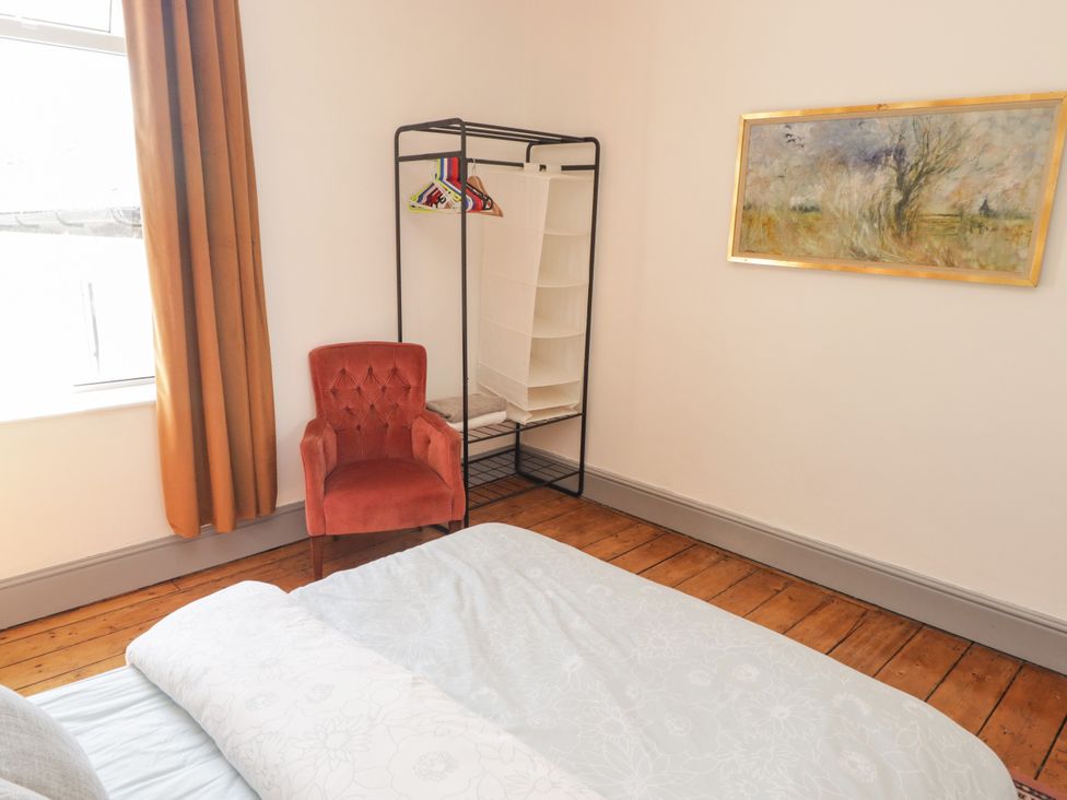 A bedroom with a bed, chair, and clothes rack at 18 Kent Street Cardiff