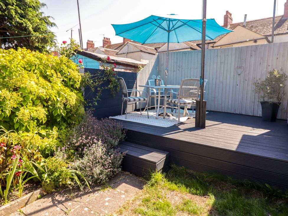 A garden with a decking area, table and chairs under an umbrella at 18 Kent Street in Cardiff