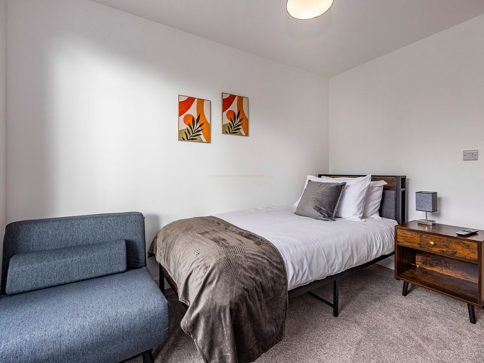 A bedroom with a bed and a sofa at 2 Riverside Mews in Derby