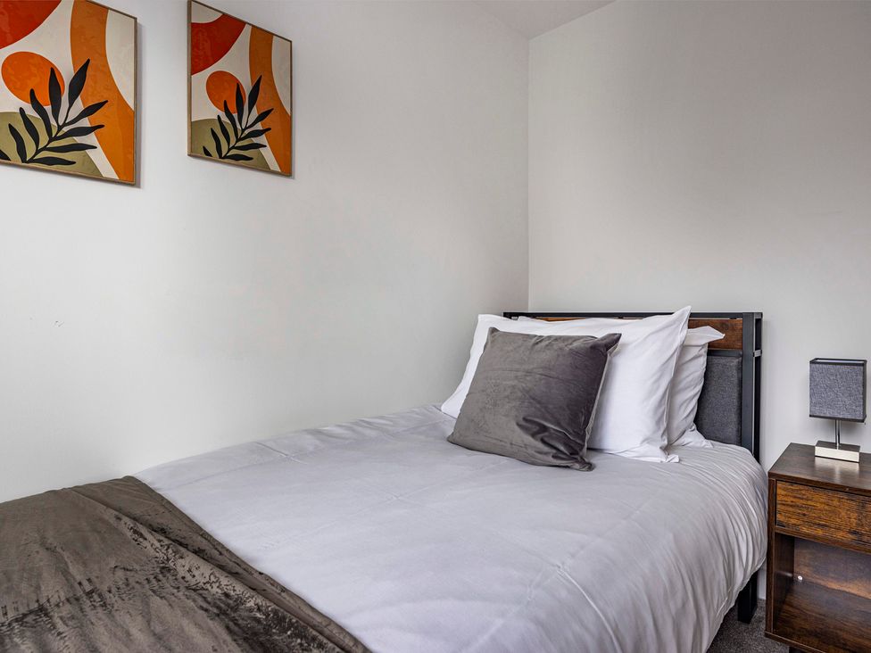 A bedroom with a bed and bedside table at 2 Riverside Mews in Derby