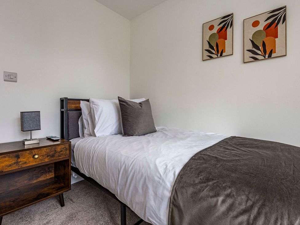 A bedroom with a bed and a side table at 2 Riverside Mews in Derby