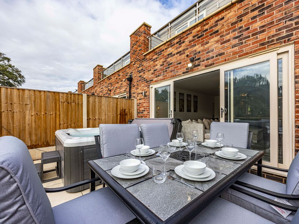 An outdoor patio with a dining table and hot tub at 2 Riverside Mews in Derby