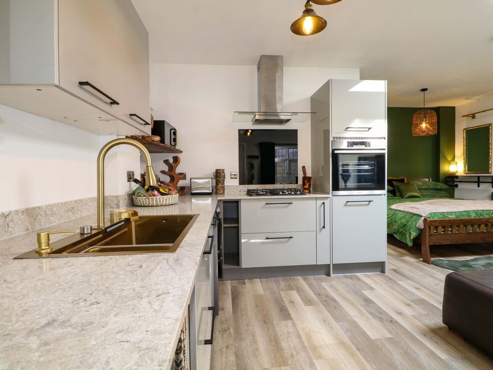 A kitchen with modern appliances and a bed at Shell Cottage in Bournemouth