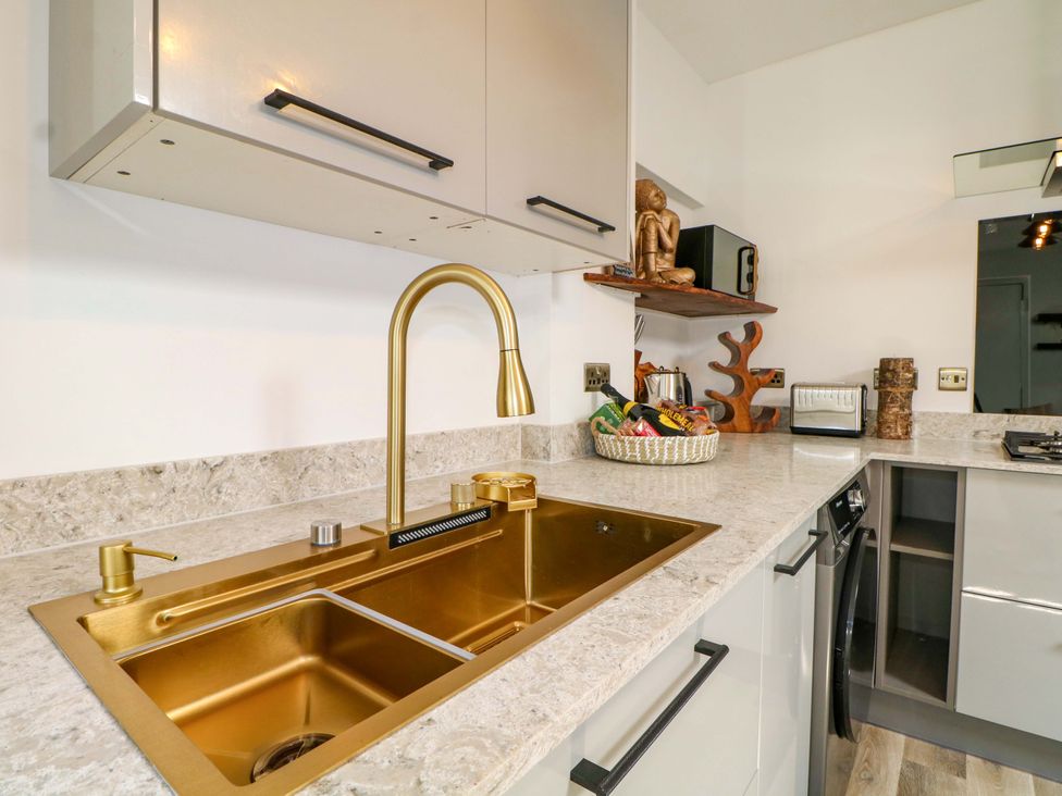A kitchen with a golden sink and faucet at Shell Cottage in Bournemouth