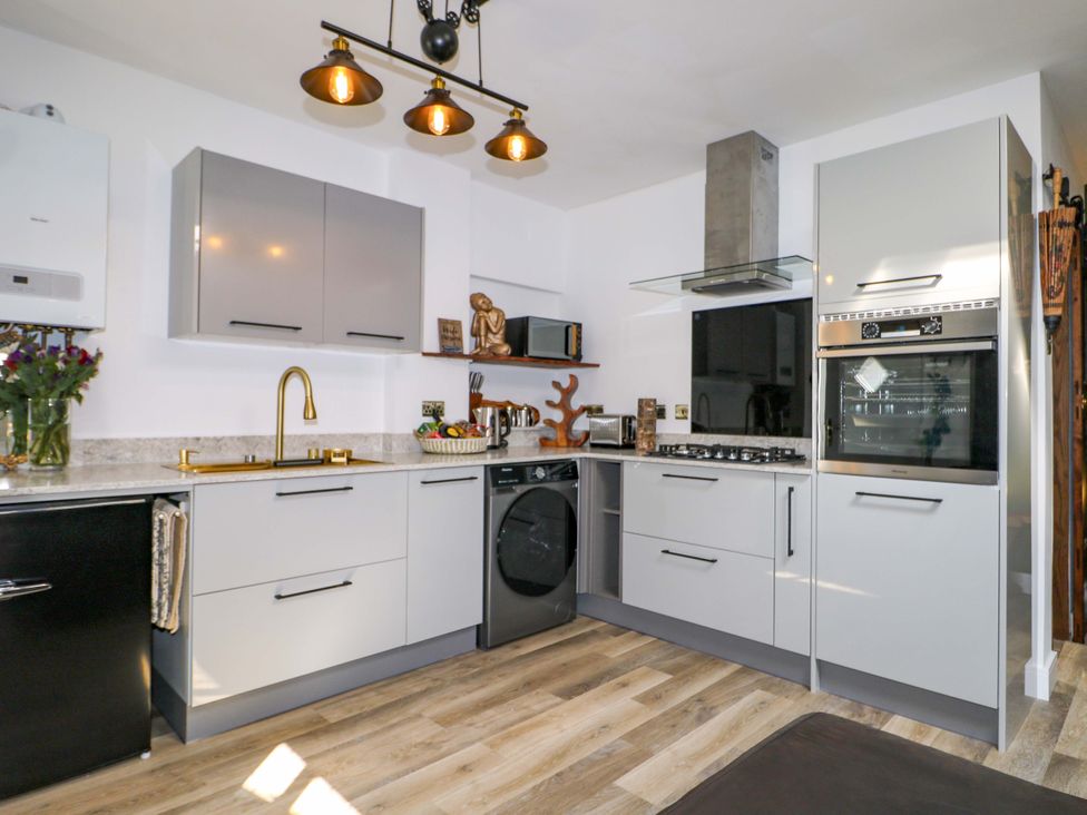 A kitchen with cabinets, stove and sink at Shell Cottage in Bournemouth