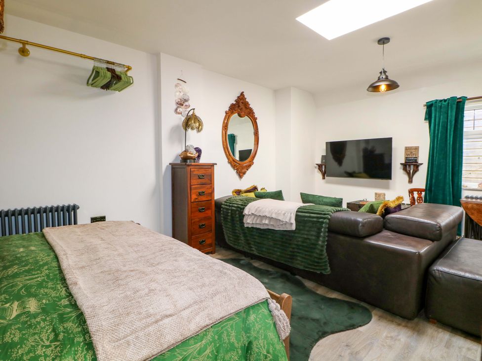 A living room with a television and a mirror at Shell Cottage in Bournemouth