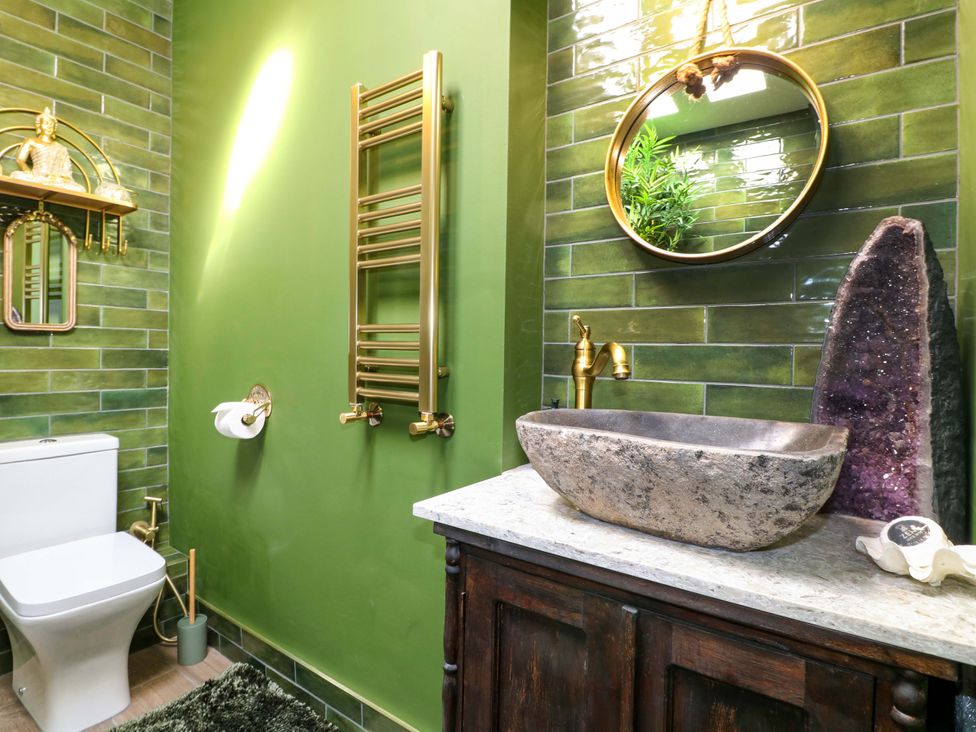 A bathroom featuring a toilet, sink, and golden fixtures at Shell Cottage in Bournemouth