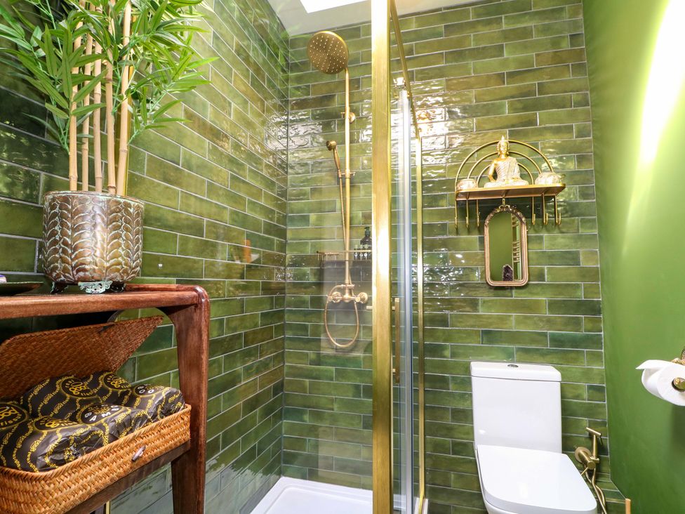 A bathroom with a shower, toilet, and decorative plant at Shell Cottage in Bournemouth