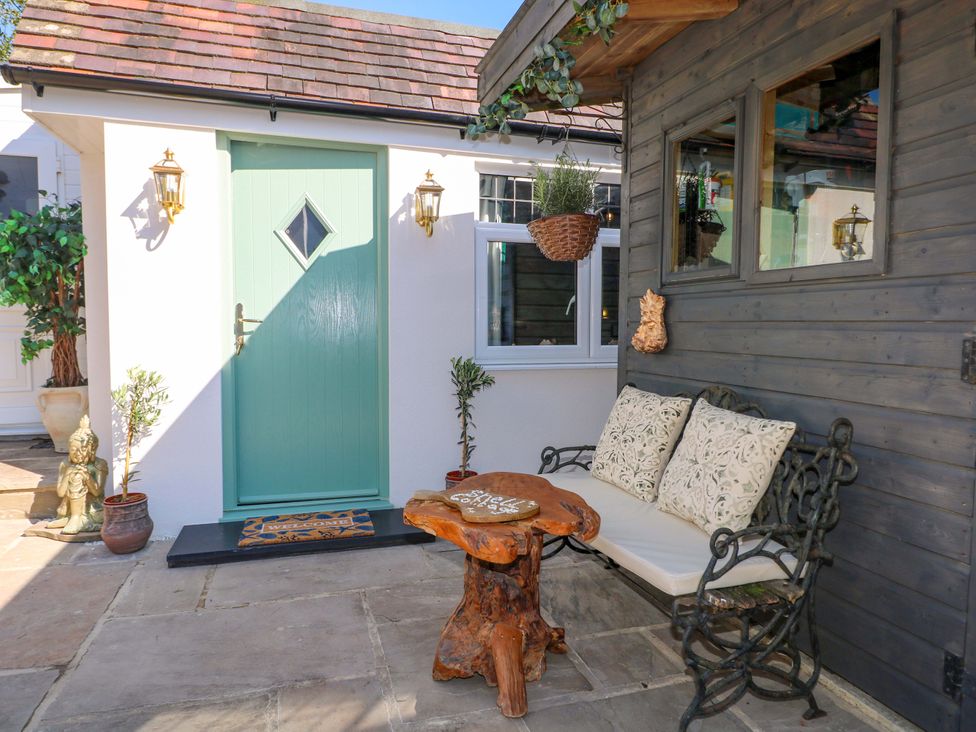 An outdoor area with a green door and a wooden bench at Shell Cottage, Bournemouth