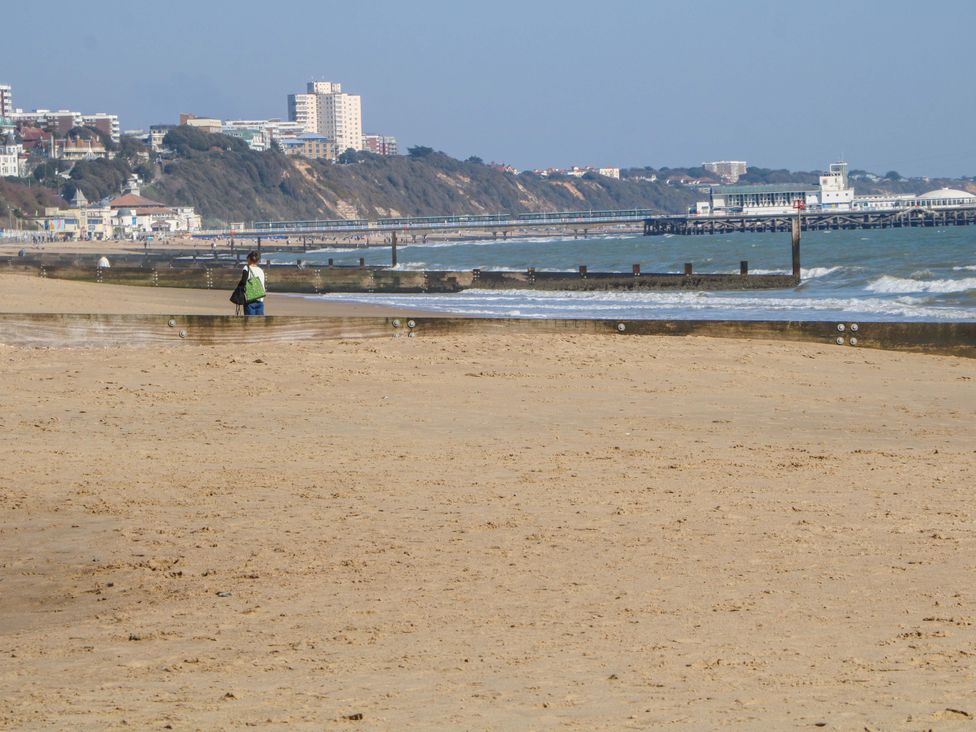 A beach with a pier and buildings in the background at Shell Cottage in Bournemouth