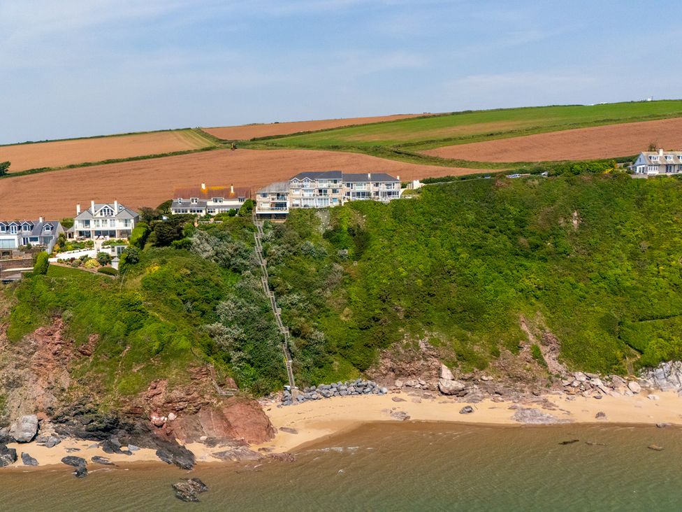 A coastal view with houses on a cliff at 6 Avon Quillet, Bigbury-On-Sea