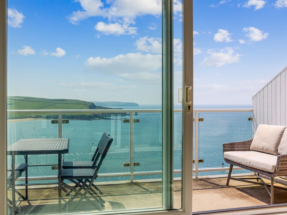 A balcony with a table and chairs overlooking the water at 6 Avon Quillet Bigbury-On-Sea