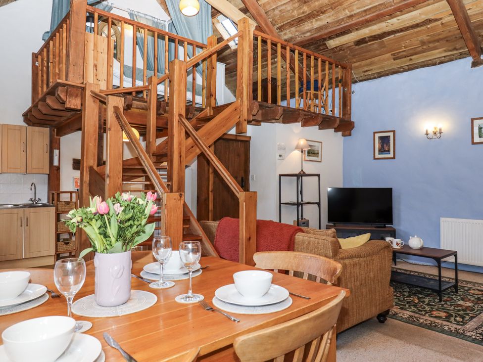 A living room with a staircase and kitchen area at Swallows Nest in Widecombe-in-the-Moor near Postbridge