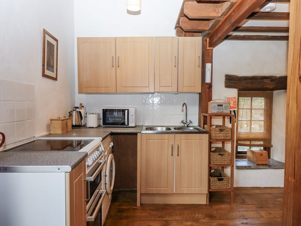 A kitchen with cabinets, stove, sink, and appliances at Swallows Nest in Widecombe-in-the-Moor near Postbridge