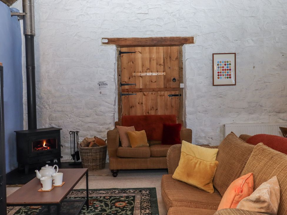 A living room with a wood stove and sofa at Swallows Nest near Widecombe-in-the-Moor