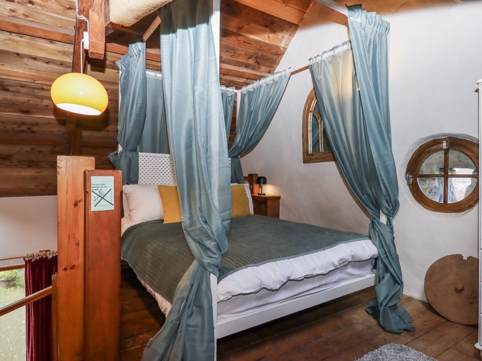 A bedroom with a bed and curtains at Swallows Nest in Widecombe-in-the-Moor near Postbridge