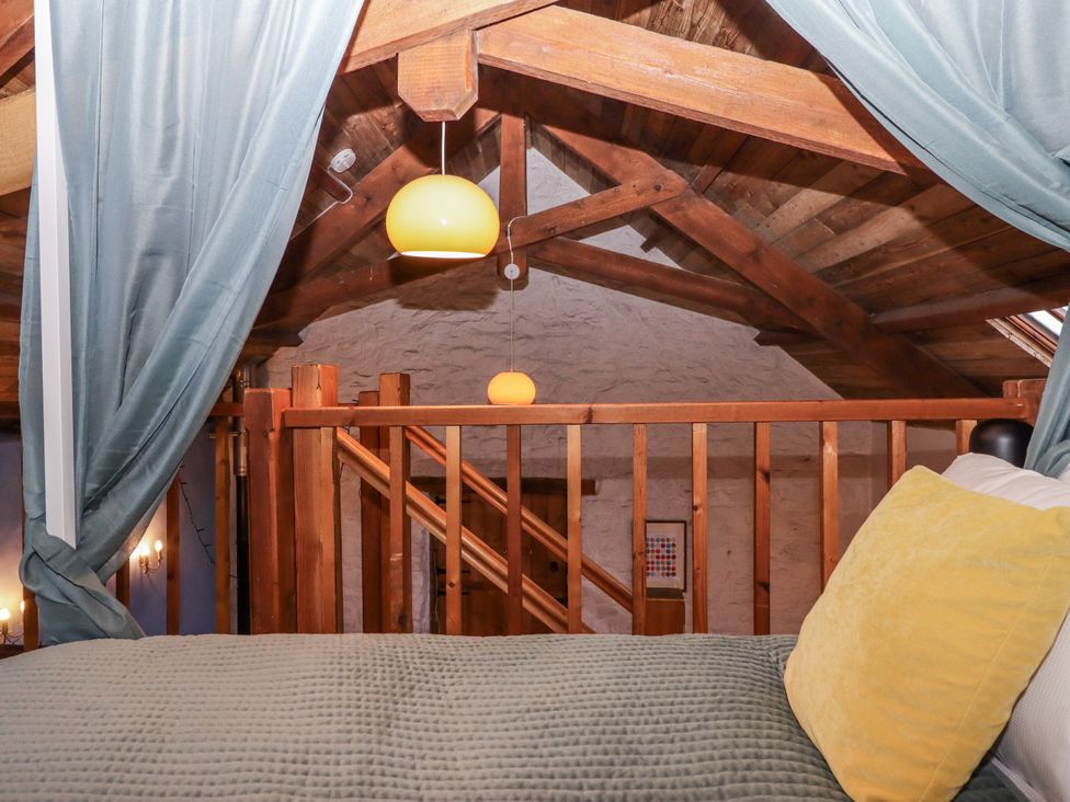 A loft with a bed and railing at Swallows Nest in Widecombe-in-the-Moor near Postbridge