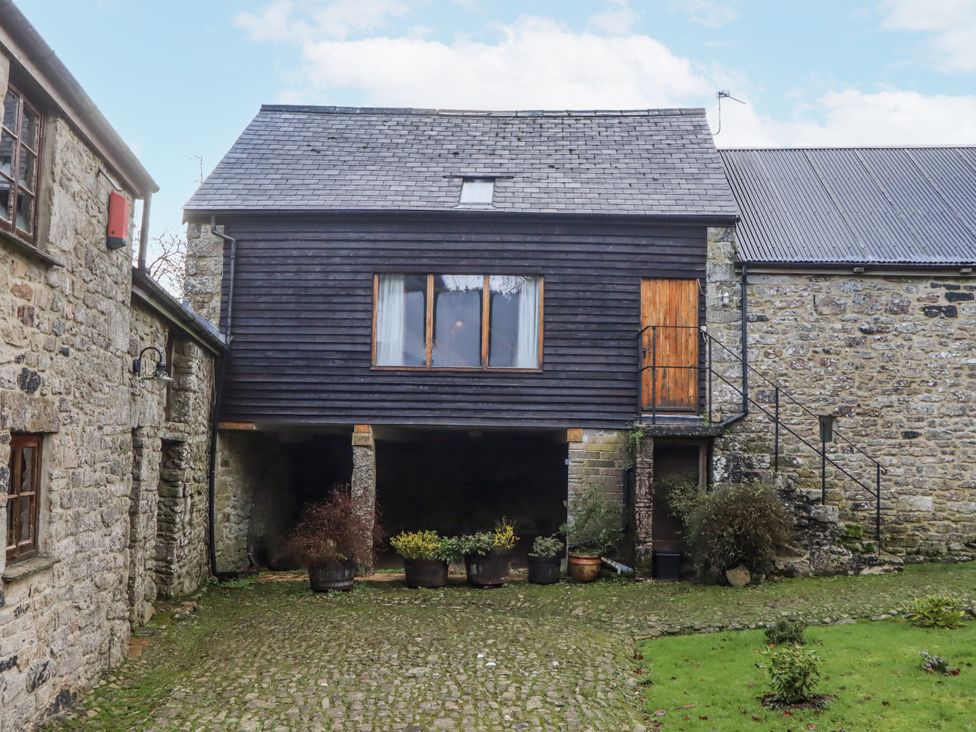 A building with a wooden upper level and potted plants at Swallows Nest Widecombe-in-the-Moor near Postbridge