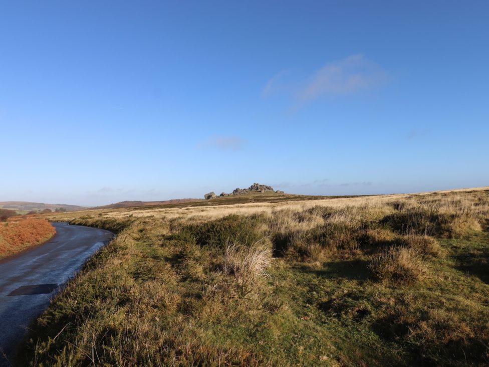 A path along grassland with rocks in the distance at Swallows Nest Widecombe-in-the-Moor near Postbridge