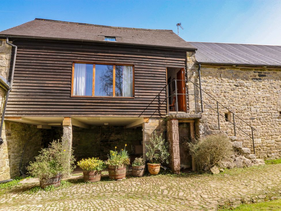 An outdoor view of a building with a wooden upper level and stone lower level at Swallows Nest Widecombe-in-the-Moor near Postbridge