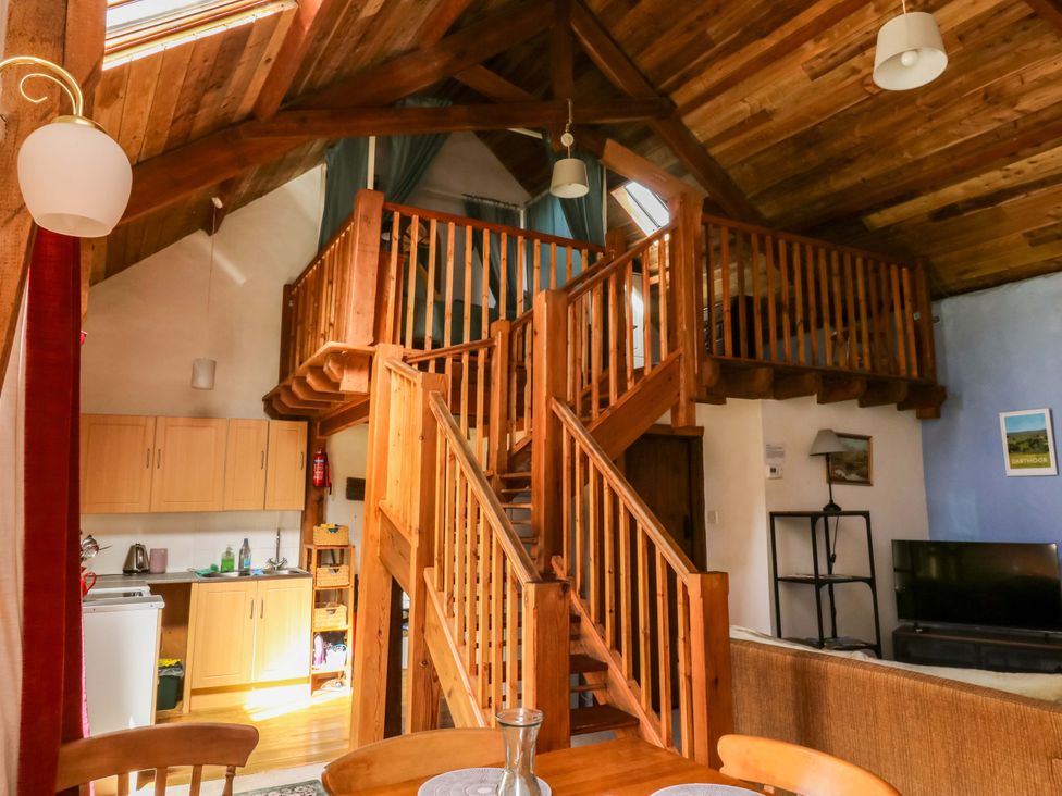 A living room with a staircase and kitchen area at Swallows Nest Widecombe-in-the-Moor near Postbridge