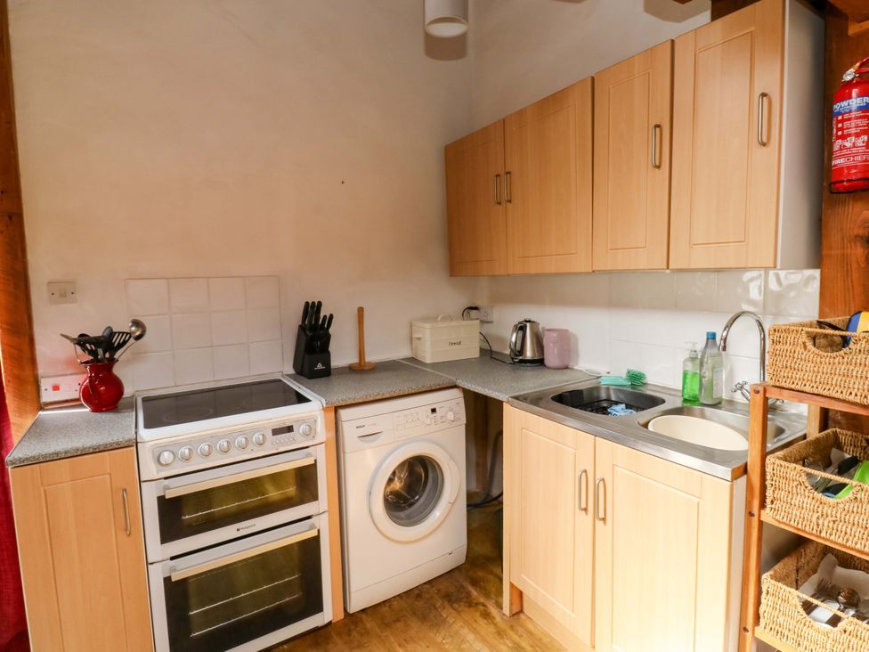 A kitchen featuring an oven, washing machine, sink and cabinets at Swallows Nest Widecombe-in-the-Moor near Postbridge