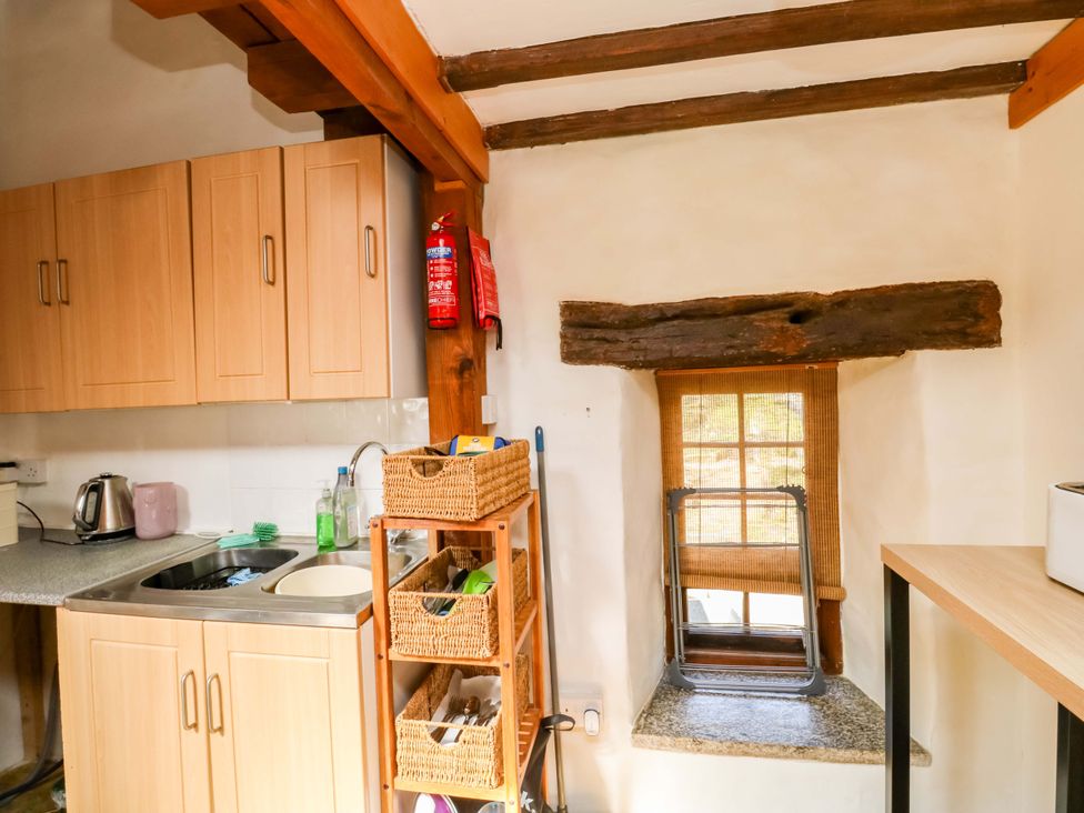 A kitchen with cabinets, sink, and window at Swallows Nest Widecombe-in-the-Moor near Postbridge