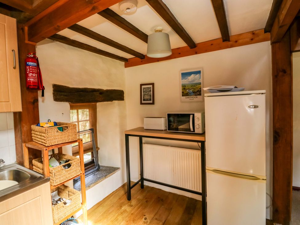 A kitchen with fridge, microwave and shelves at Swallows Nest in Widecombe-in-the-Moor near Postbridge