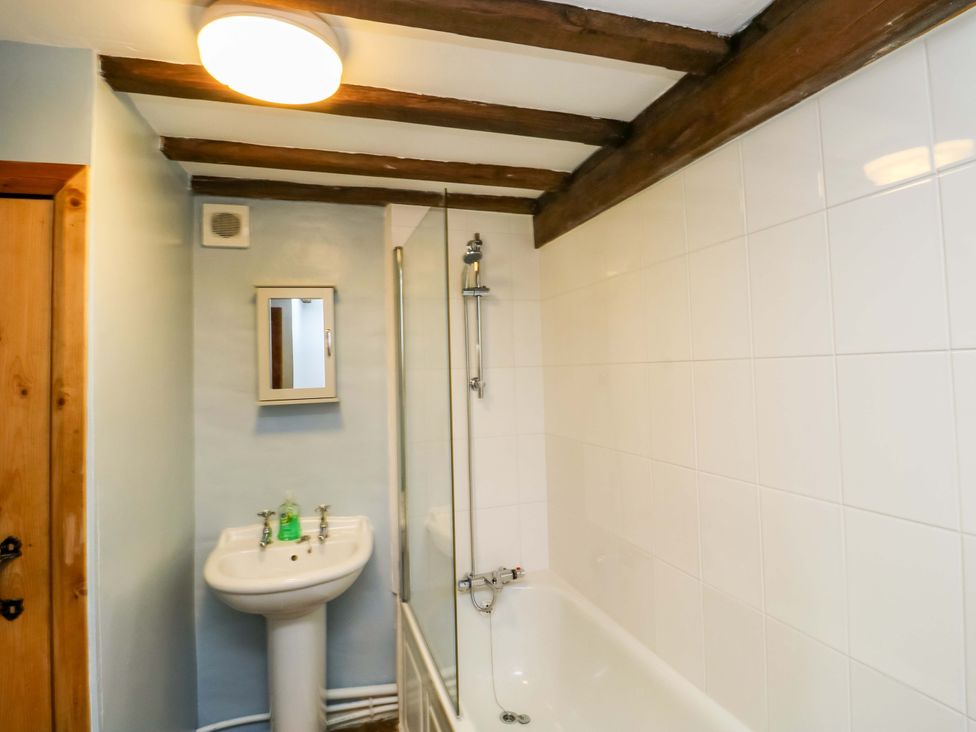 A bathroom with a bath tub, sink, and mirror at Swallows Nest in Widecombe-in-the-Moor near Postbridge