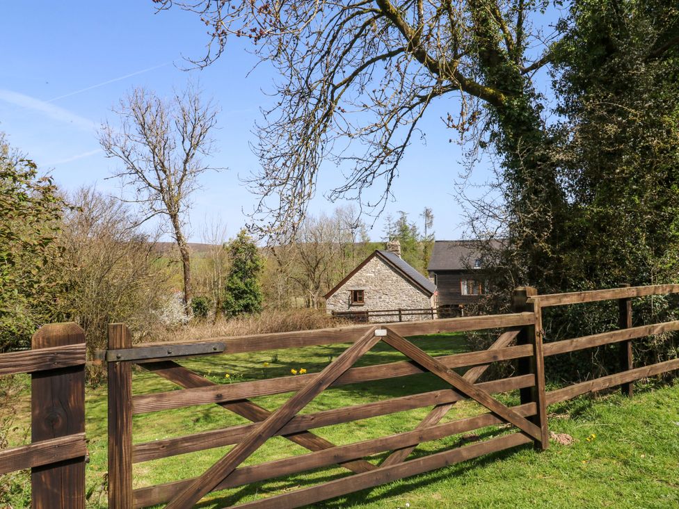 A wooden gate in front of stone and wooden houses with trees at Swallows Nest near Widecombe-in-the-Moor